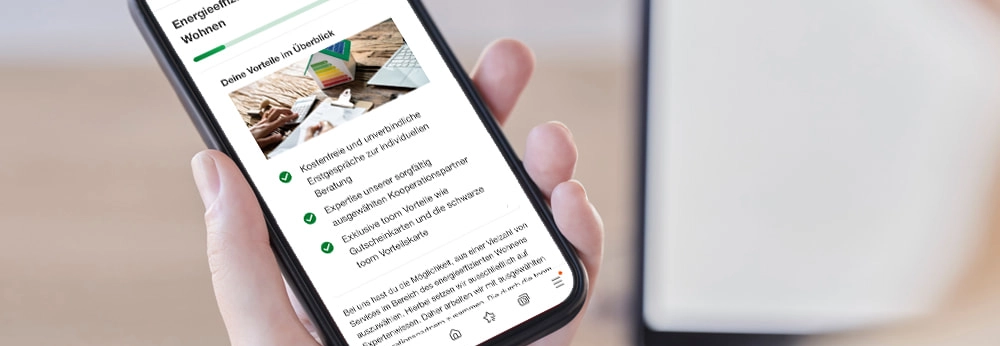 Person hält Smartphone mit Screen zu energieeffizienten Wohnen in der Hand